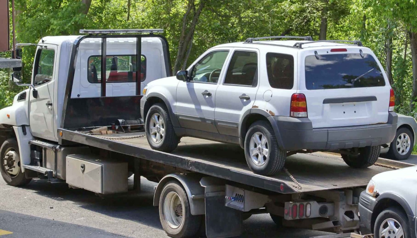 Flatbed towing service transporting SUV on highway in Pembroke Pines, FL